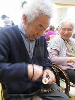 手作り恵方巻きに海苔を巻いている利用者様