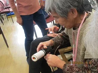 手作り恵方巻きに海苔を巻いている利用者様