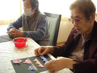 折り紙で雛飾りを作っている入居者様たち